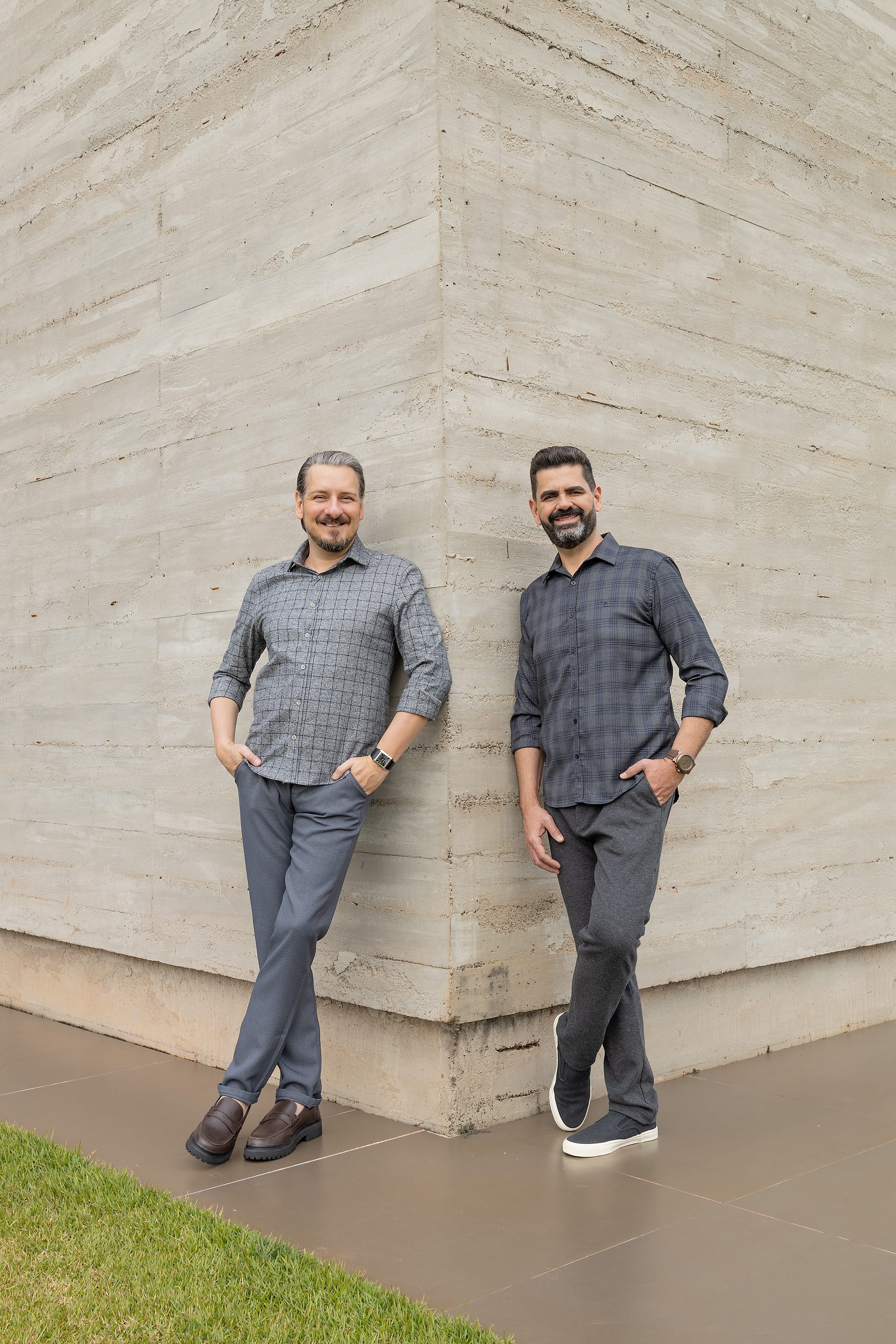 Alessandro and Ricardo, the firm’s founders, standing side by side in a relaxed pose and smiling.
