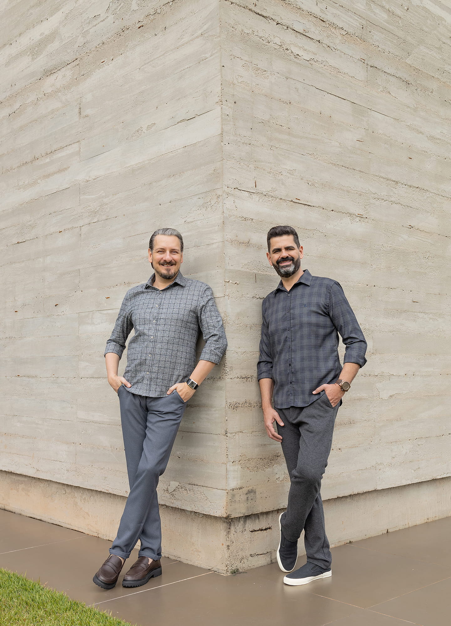 Alessandro and Ricardo, the firm’s founders, standing side by side in a relaxed pose and smiling.